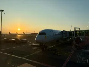 A| picture of a plane on a runway with a sunset in the background.