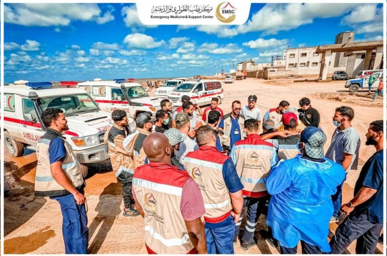 a group of several medical professionals in Libya huddling around ambulances